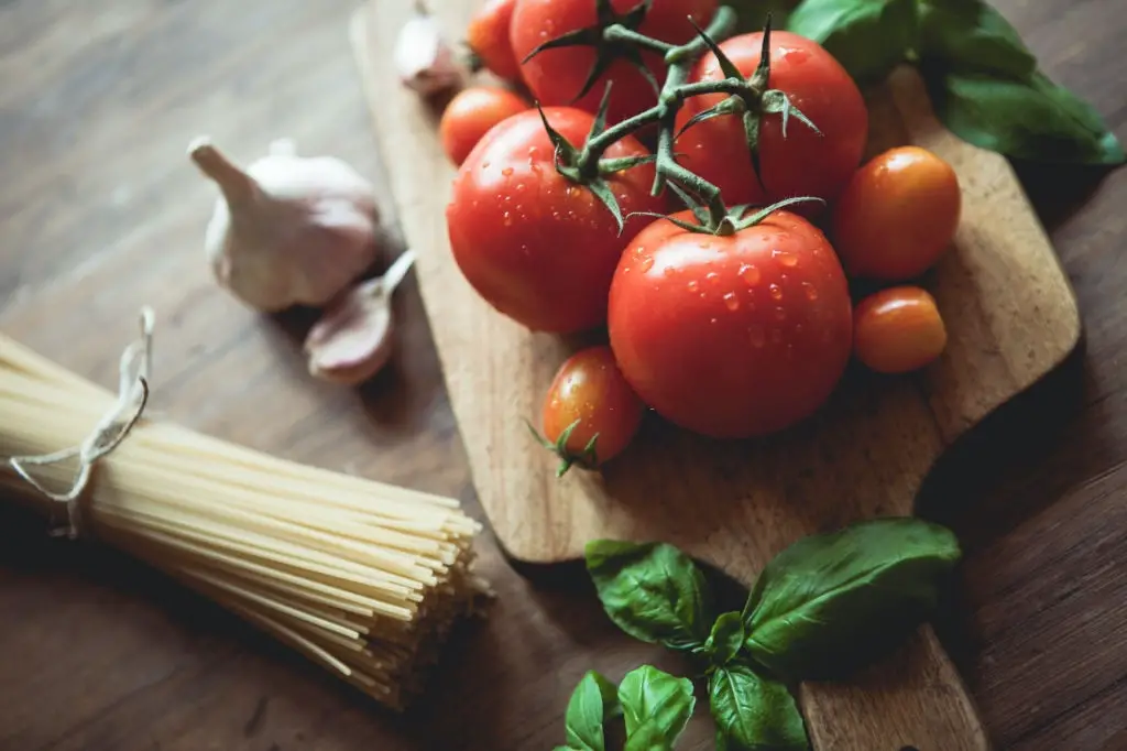 Spaghetti, garlic, basil and tomatoes on a cutting board. Raw food.